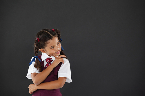 Thoughtful schoolgirl standing against blackboard in classroom