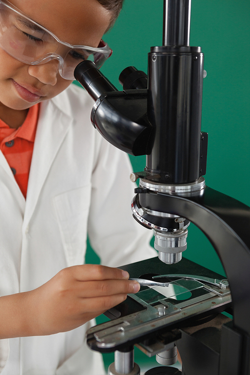 Schoolboy using microscope in laboratory
