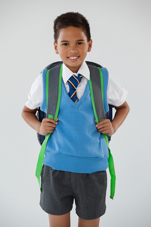 Portrait of schoolboy in school uniform with school bag on white background