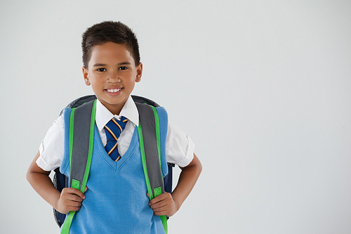Portrait of schoolboy in school uniform with school bag on white background