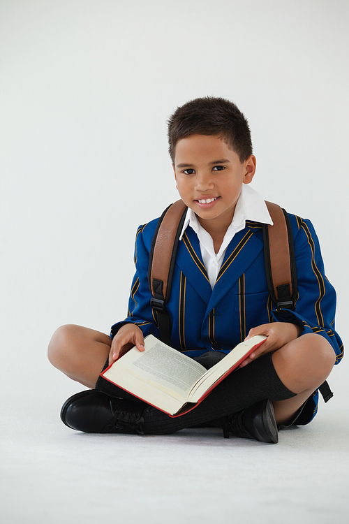 Portrait of schoolboy reading book on white background