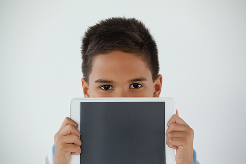 Portrait of schoolboy holding digital tablet against white background