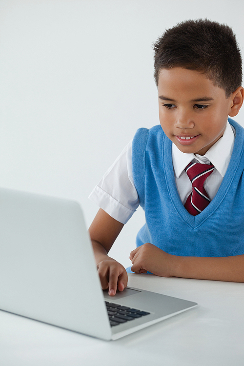 Schoolboy using laptop against white background