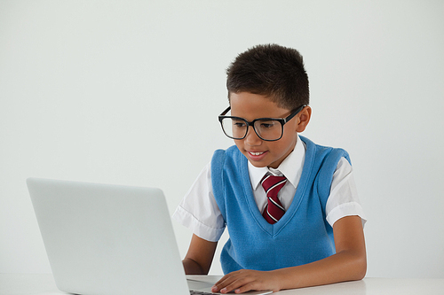 Schoolboy using laptop against white background
