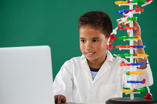 Smiling schoolboy experimenting molecule model in laboratory at school