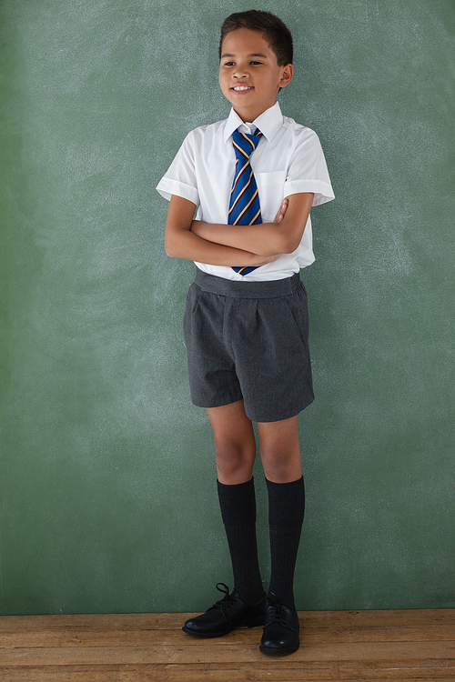 Schoolboy standing in front of chalkboard in classroom at school