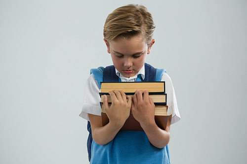 Close-up of schoolboy holding books against white background