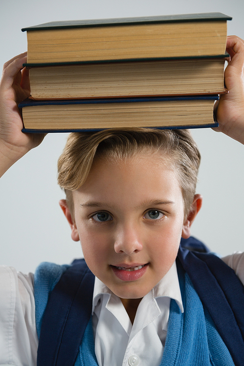 Portrait of schoolboy holding her book on her head