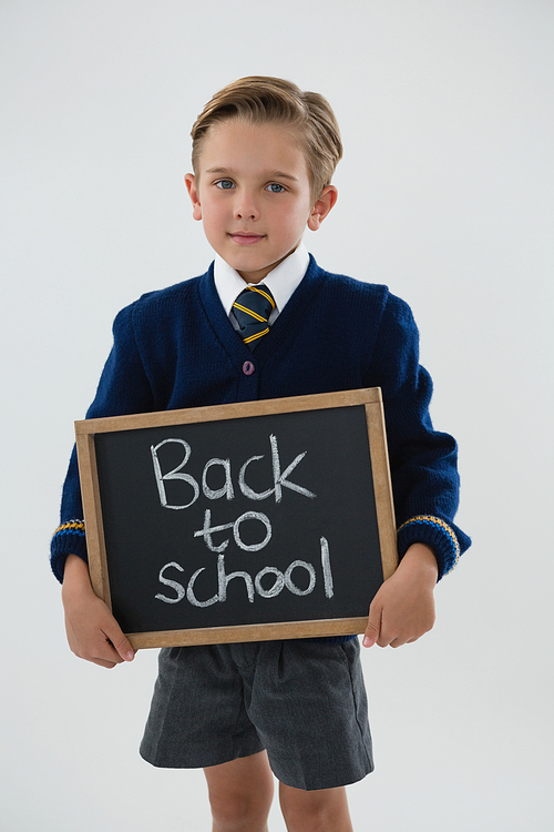 Portrait of schoolboy holding slate with text against white background