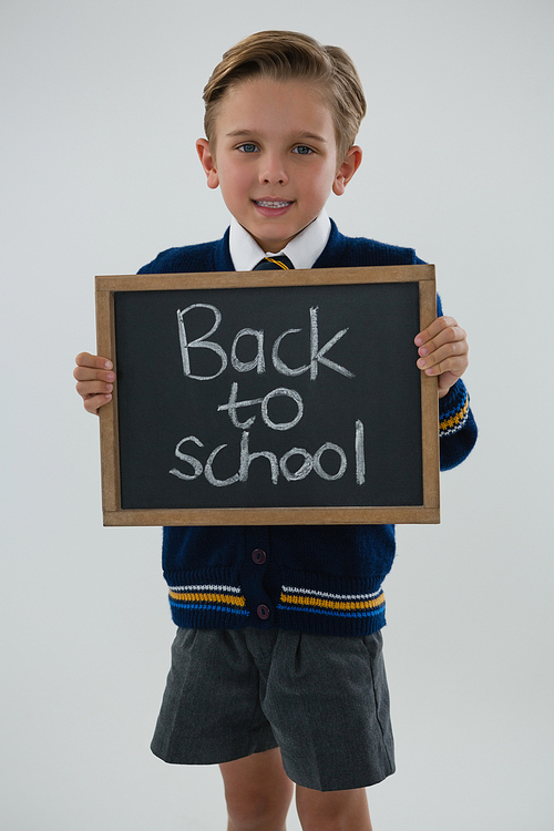 Portrait of schoolboy holding slate with text against white background