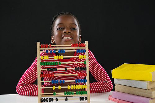 Portrait of cute girl with abacus against black background