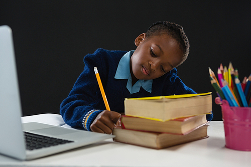 Schoolgirl doing homework against black background