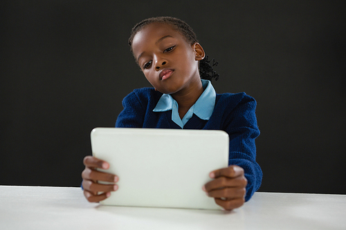 Schoolgirl using digital tablet against black background