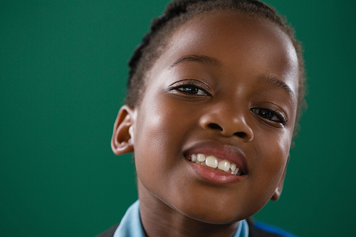 Portrait of smiling schoolgirl against green background