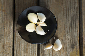 Overhead of garlics in plate on wooden table