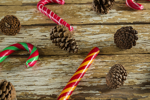 Candy canes and pine cones on weathered wooden plank
