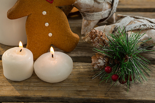 Close up of gingerbread cookie with star shape decorating and illuminated candles on wooden table
