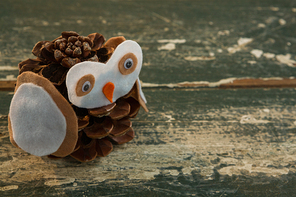 Close up of owl decoration made with pine cone on wooden table