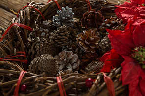 Close up of artificial nest with pine cones and poinsettia flowers on wooden table