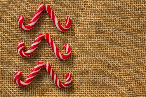 Overhead view of candy canes arranged on burlap