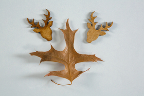 Close up of autumn leaf with wooden reindeer head on white table