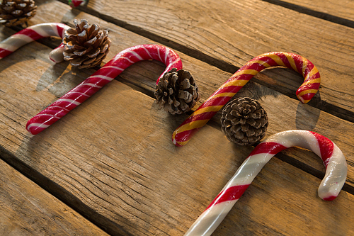 Colorful candy canes with pine cones on wooden table