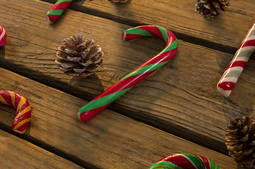 High angle view of candy canes and pine cones on wooden table