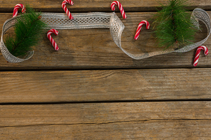 High angle view of candy canes with twigs and ribbon on wooden table