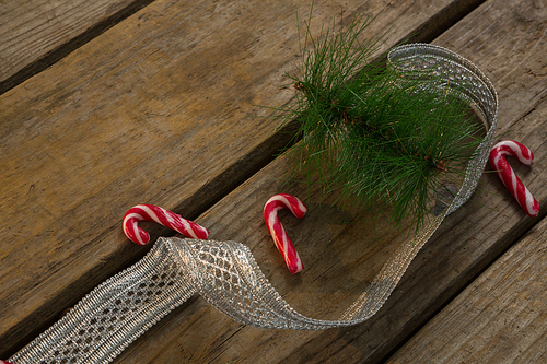 High angle view of candy canes with twigs and ribbon on table