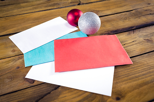 Close-up of envelopes and christmas baubles on wooden table