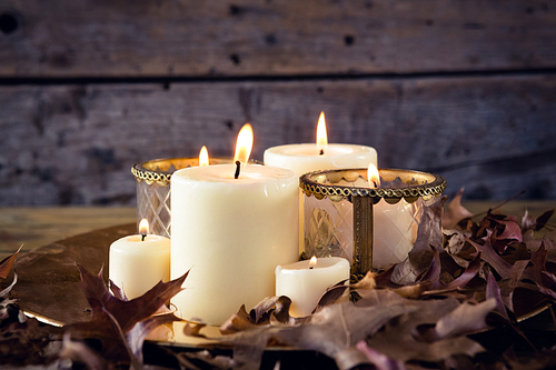 Close-up of lit candles and dry leaves on table