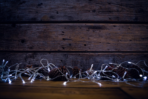 Christmas light and pine cones on wooden plank during christmas
