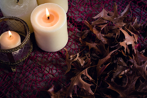 Close-up of lit candles and dry leaves on table