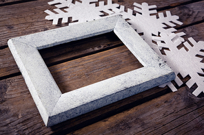 Close-up of handmade frame and snowflake on wooden plank