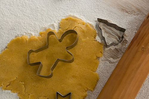Gingerbread dough with flour, cookie cutter and rolling pin on wooden table