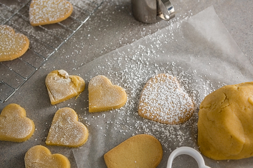 Raw heart shape cookies with sugar icing on wax paper on table