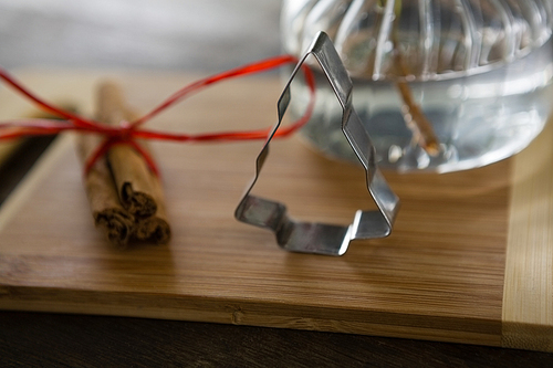 Close-up of wrapped cinnamons and cookie cutter on chopping board