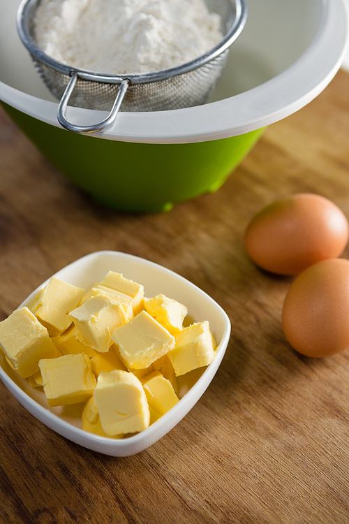 Flour in strainer with eggs and cheese on wooden table