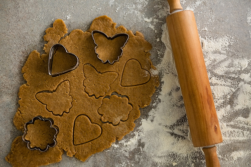 Close-up of gingerbread dough with flour, cookie cutter and rolling pin on table