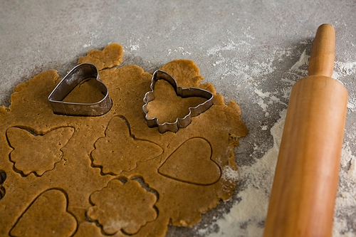 Close-up of gingerbread dough with flour, cookie cutter and rolling pin on table