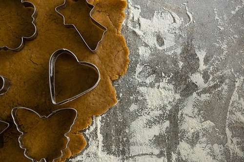 Close-up of gingerbread dough with flour and cookie cutter on table