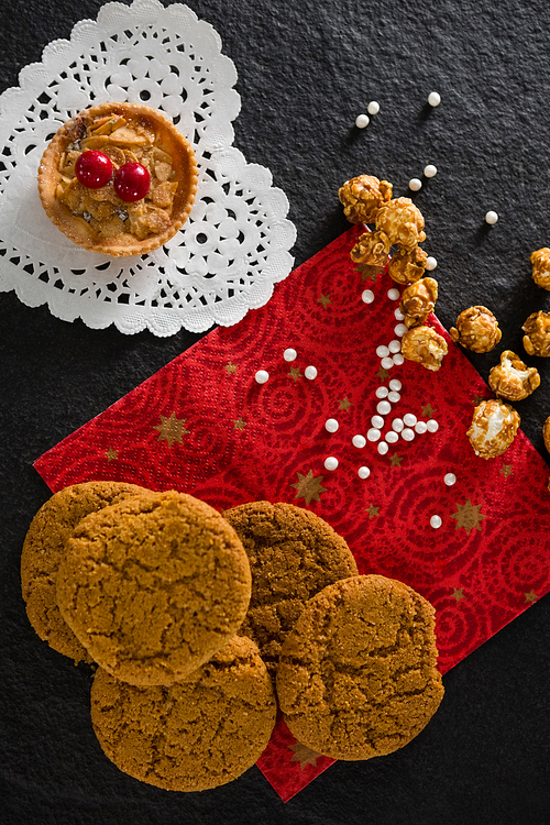 Overhead of tart and cookies with pearls on red place mat