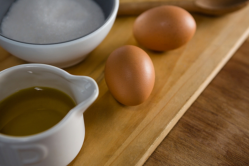 Close-up of brown eggs and sugar on chopping board