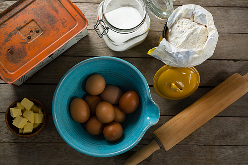 Overhead view of brown eggs and ingredients on wooden plank