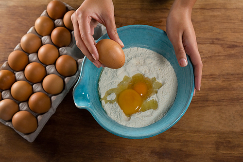 Mid-section of man breaking eggs in the flour in bowl