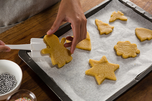 Mid-section of man placing gingerbread cookies in baking tray