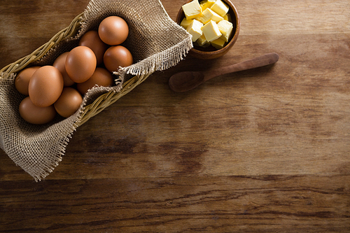 Overhead view of brown eggs and cheese cubes on a wooden table