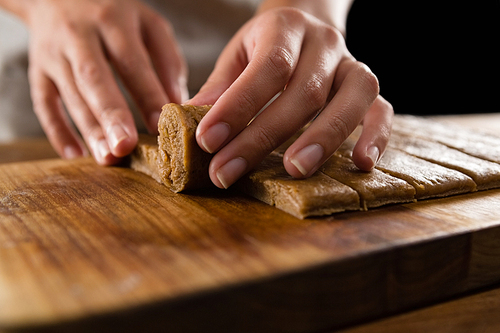 Close-up of woman arranging dough on chopping board