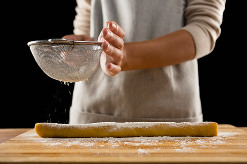 Mid-section of woman icing sugar on dough