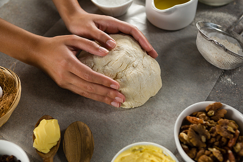 Close-up of woman preparing dough surrounded with various ingredients